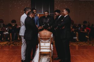 groom and fraternity brothers pray around bride at Baton Renaissance Hotel wedding